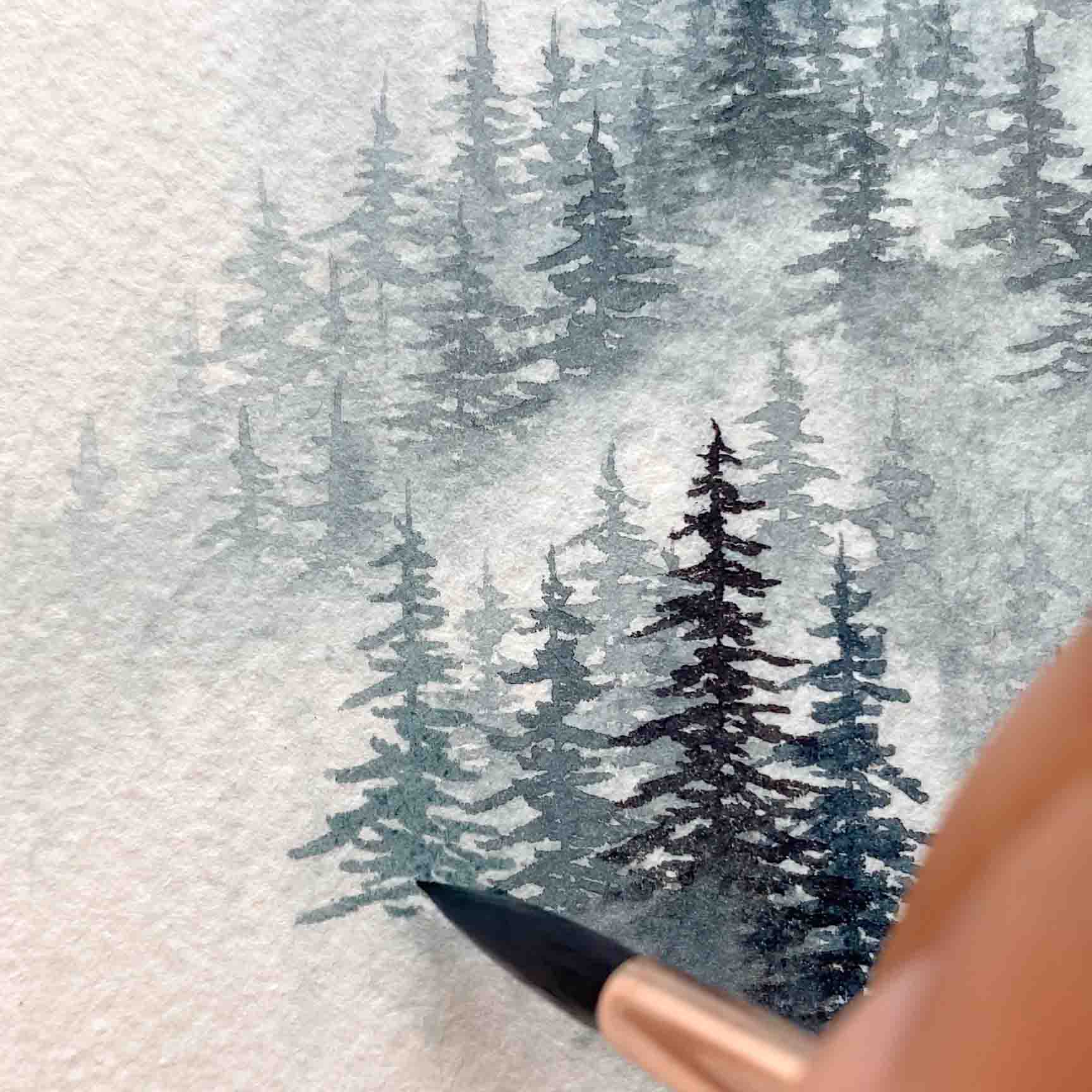 A close-up shot of a woman painting a misty mountain in watercolor.